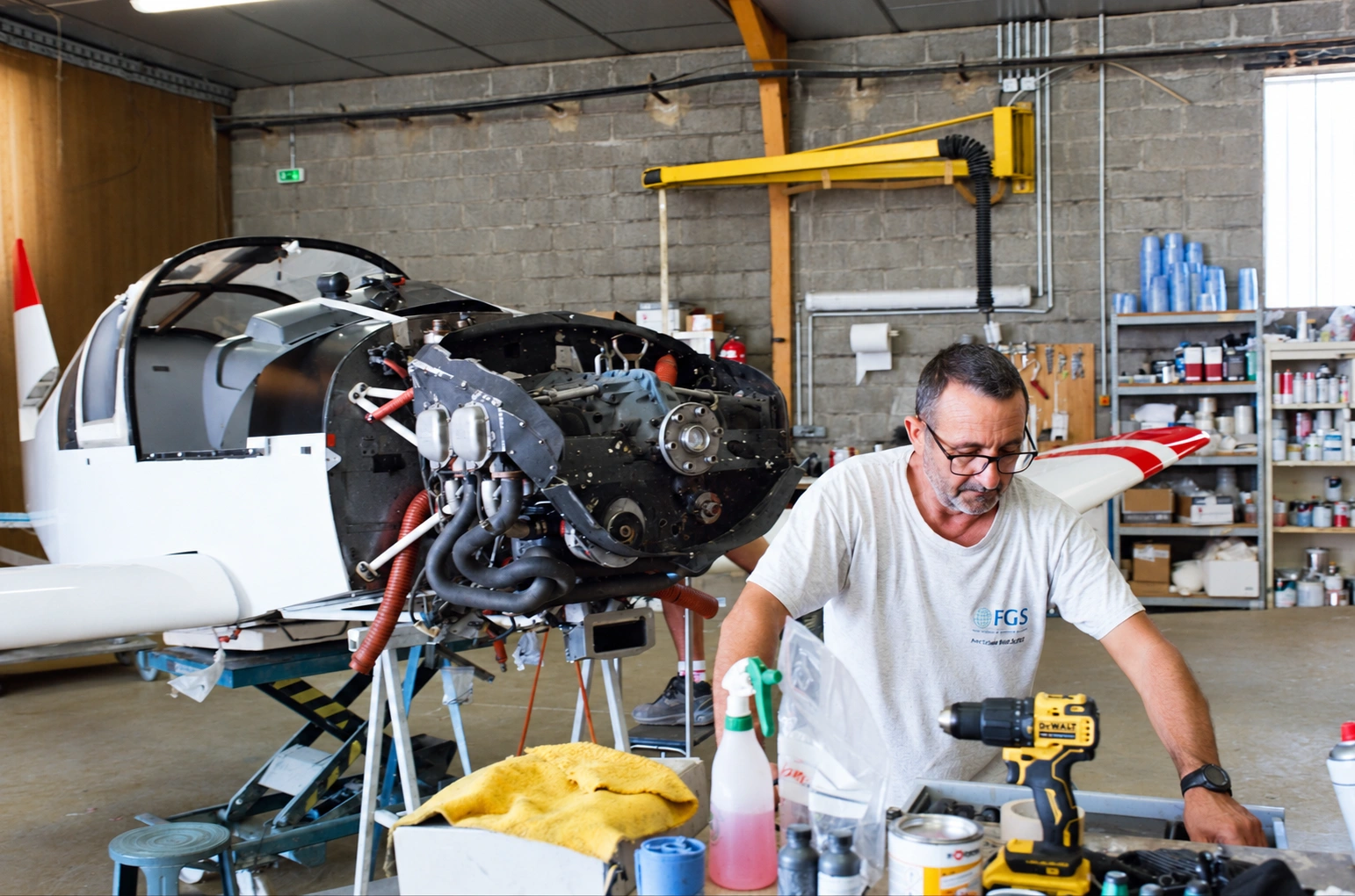 Un technicien FGS travaille à son établi, devant le F-GLKP en cours de remontage.