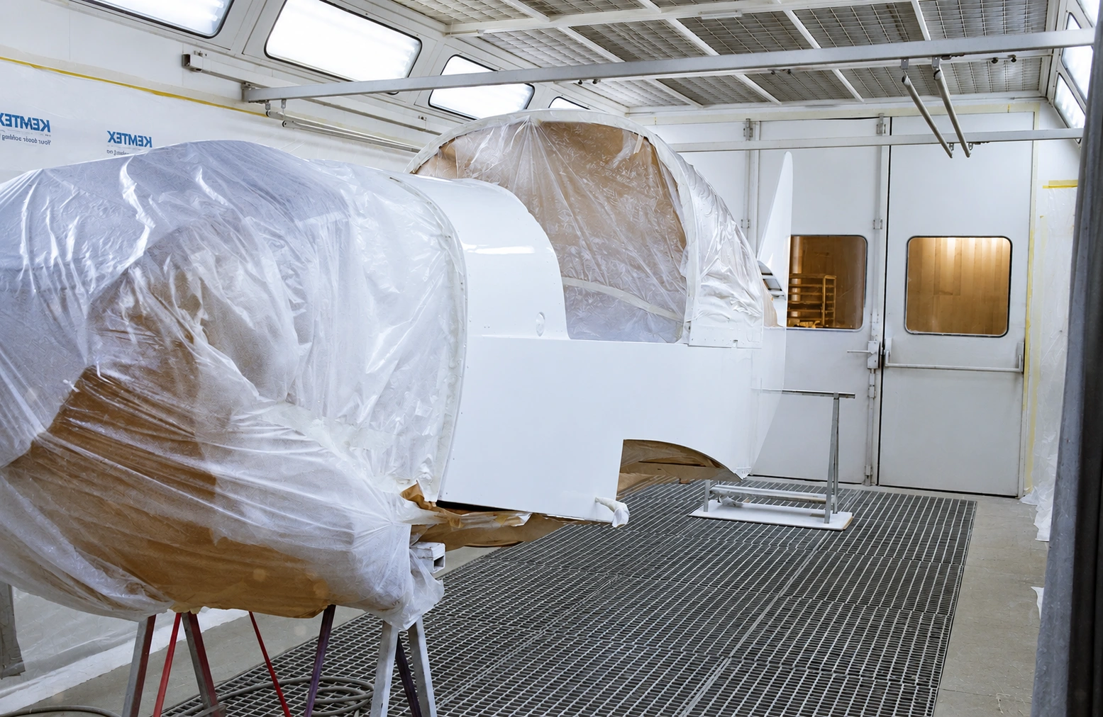 Fuselage du F-GLKP protégé par un masquage dans la cabine de peinture.