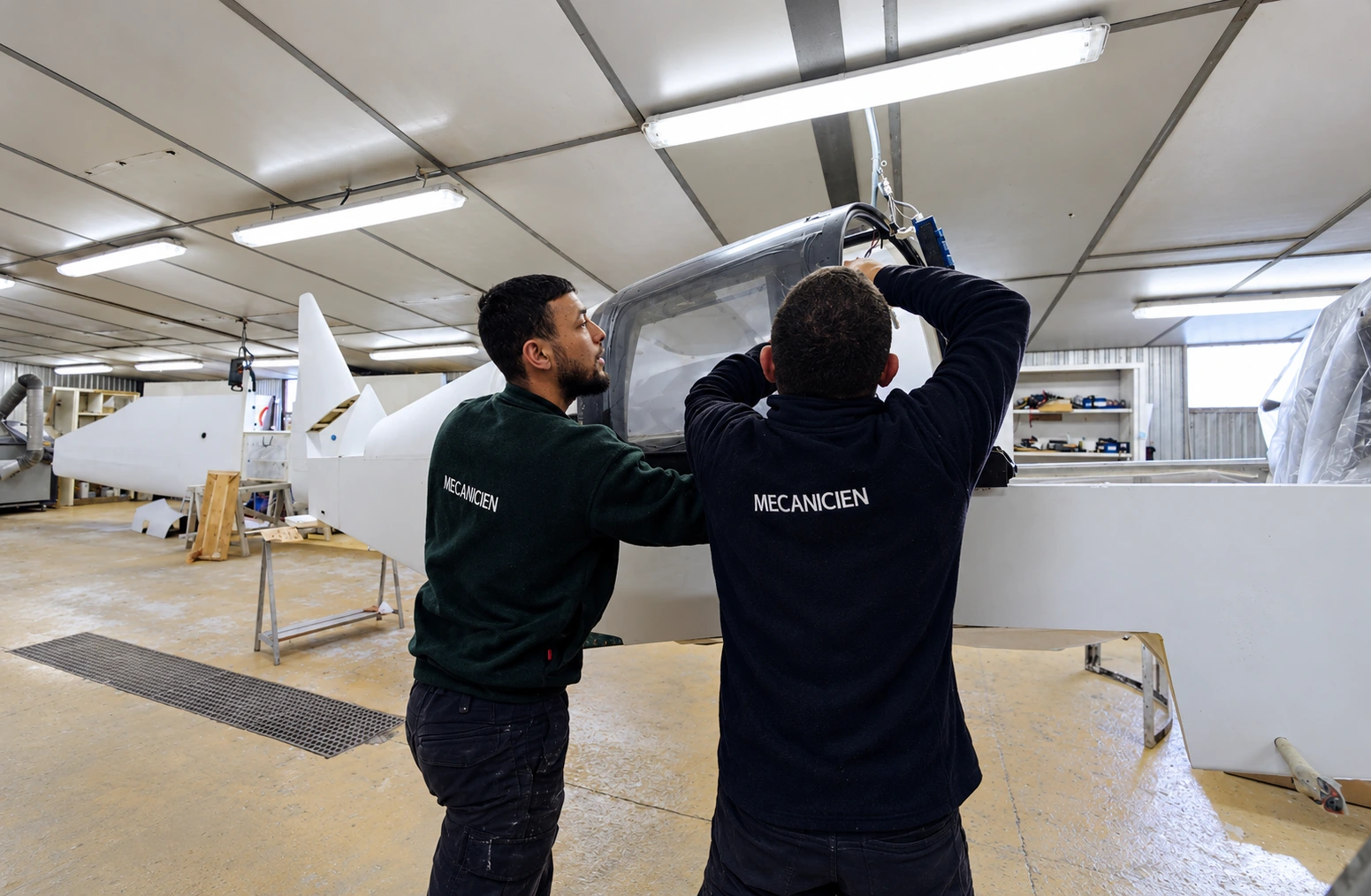 Deux mécaniciens FGS travaillent ensemble sur la cellule d’un aéronef dans l’atelier.